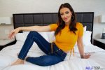 Beautiful hot mom poses in bed wearing jeans and top